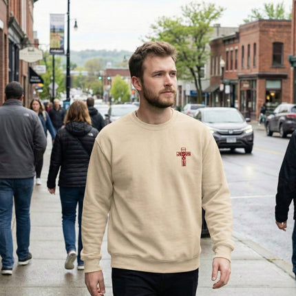 Man walking on a city street wearing a beige sweatshirt with a red logo.