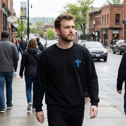 Man walking on a city street wearing a black sweatshirt with a blue logo.